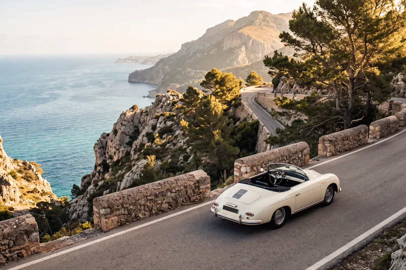Cremeweißes Oldtimer-Cabrio auf der Küstenstraße der Serra de Tramuntana über dem Meer auf Mallorca