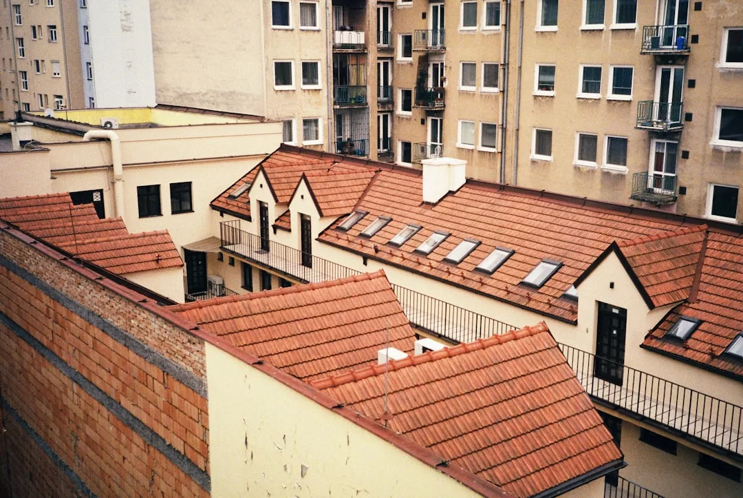 Blick auf rot geflieste Dächer und beigefarbene Wohnhäuser mit Fenstern und Balkonen in einem städtischen Wohngebiet auf Mallorca.