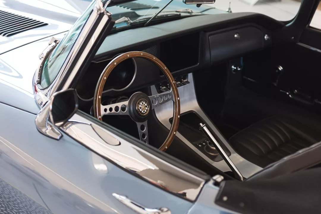Innenansicht eines klassischen Cabriolets auf Mallorca mit Holzlenkrad, schwarzen Ledersitzen und alten Bedienelementen am Armaturenbrett.