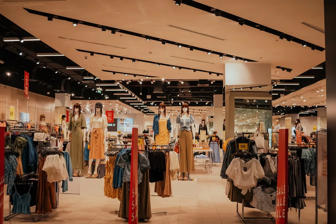 Bekleidungsgeschäft auf Mallorca mit Schaufensterpuppen, die Outfits präsentieren, Kleiderständern und Verkaufsschildern, die in dem hell erleuchteten Raum sichtbar sind.
