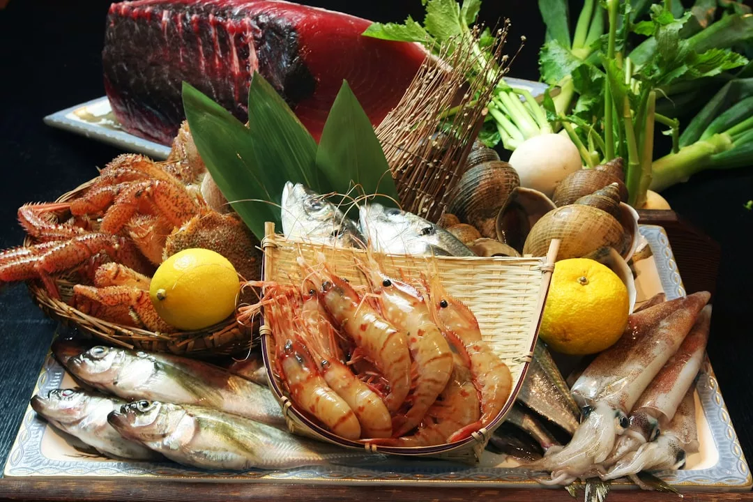 Eine Platte mit verschiedenen frischen Meeresfrüchten, inspiriert von Mallorca, mit Garnelen, Fisch, Tintenfisch, Venusmuscheln, Hummer und einem großen Stück Thunfisch, serviert mit Zitronen und Blattgemüse.
