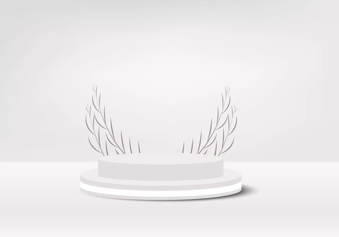 Ein weißes, rundes Podium mit zwei Lorbeerzweigen im Hintergrund vermittelt ein Gefühl von Prestige vor einem schlichten, hellgrauen Hintergrund, der an die ruhige Eleganz Mallorcas erinnert.