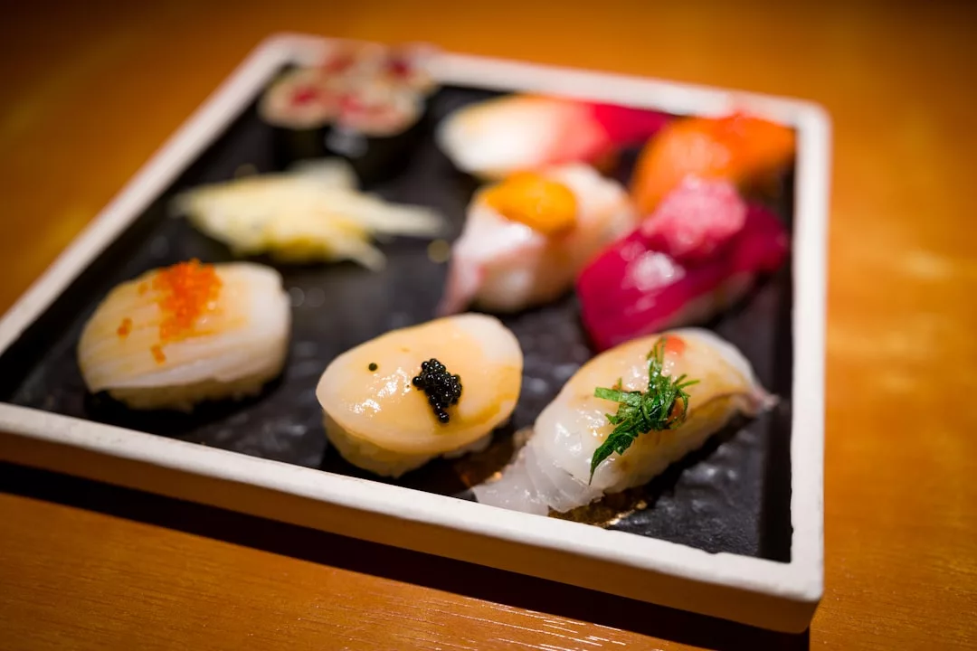 Ein quadratischer schwarzer Teller mit verschiedenen Nigiri-Sushi und Ingwer steht auf einem Holztisch und bietet einen Vorgeschmack auf Japan auf Mallorca.