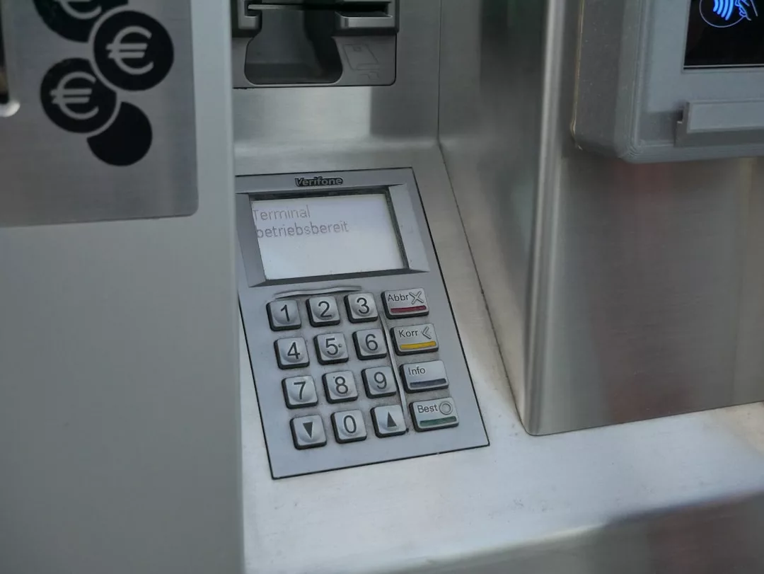 Nahaufnahme einer Geldautomatentastatur und eines Bildschirms, auf dem eine Nachricht in deutscher Sprache angezeigt wird, mit Euro-Währungssymbolen auf der linken Seite - typisch für Geldautomaten auf Mallorca.