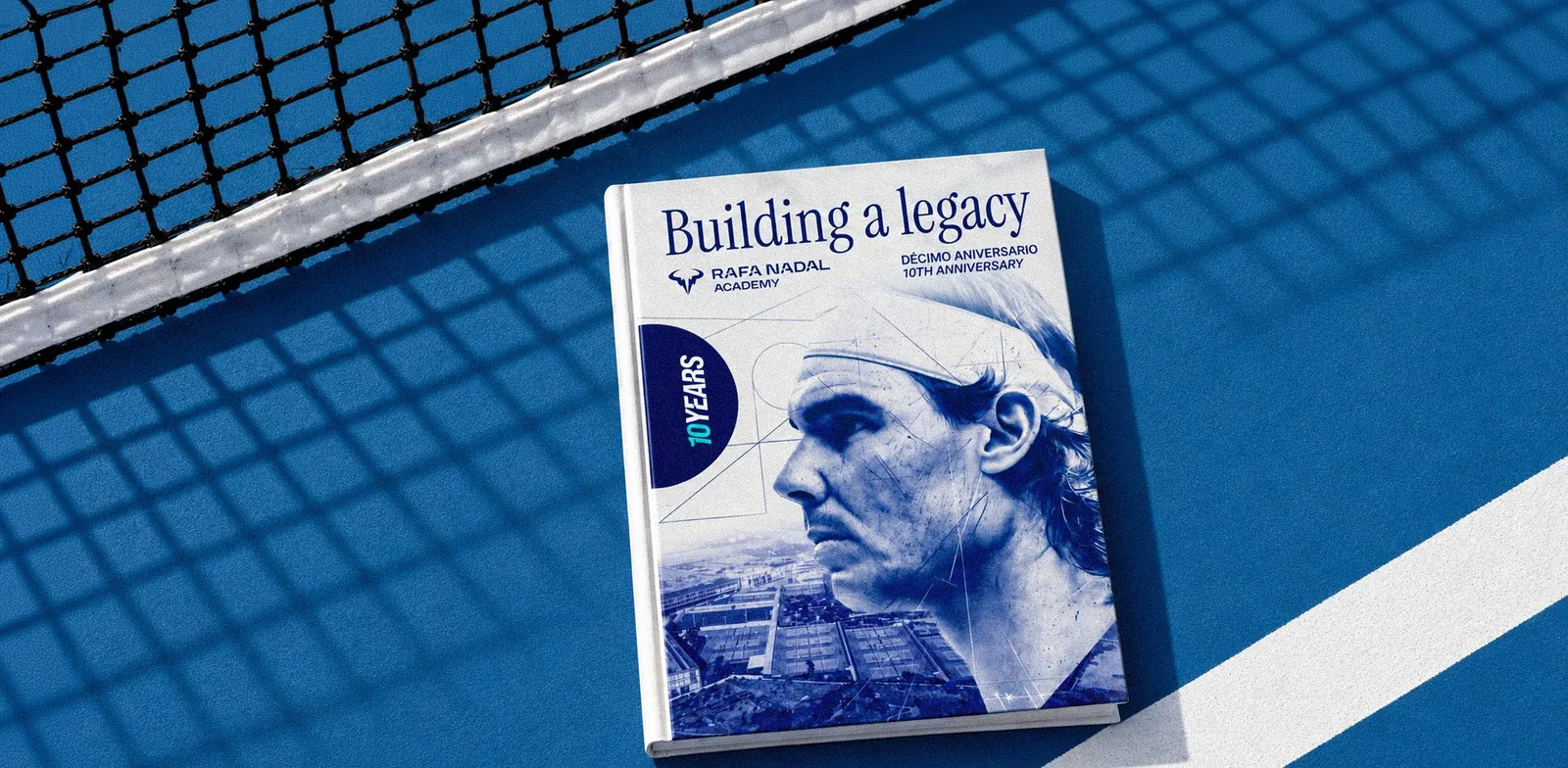 Jubiläumsbuch Building a Legacy der Rafa Nadal Academy auf einem blauen Tennisplatz