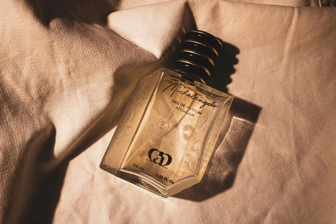 Ein gläserner Parfümflakon mit der Aufschrift "Michelangelo Eau De Parfum" ruht auf einem strukturierten, beigen Stoff unter warmer Beleuchtung, die an die sonnenverwöhnte Eleganz Mallorcas erinnert.