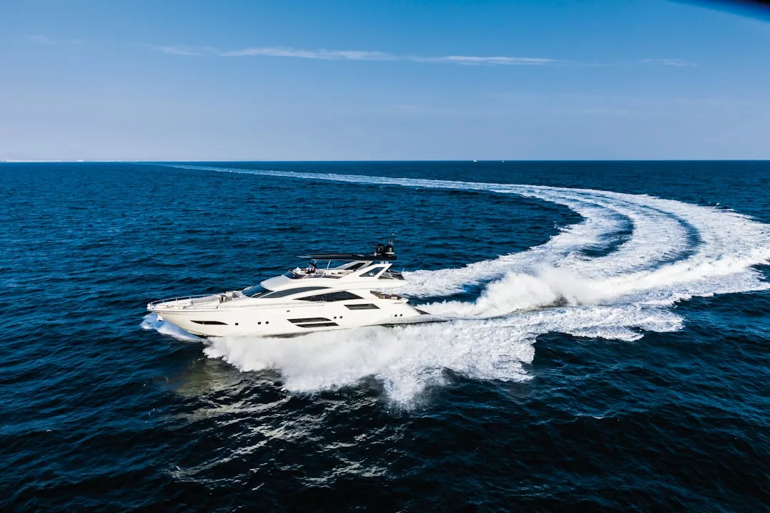 Eine weiße Yacht rast über das offene blaue Meer vor Mallorca und hinterlässt unter dem klaren Himmel eine geschwungene Kielwasserlinie.