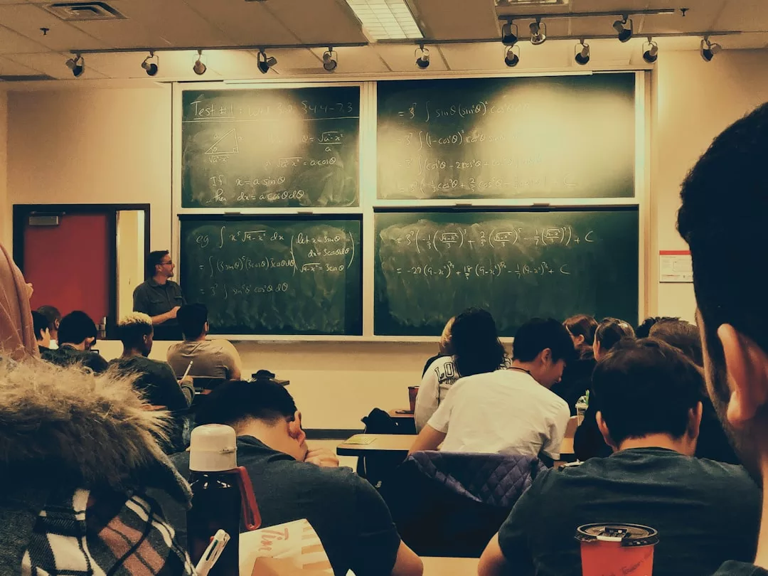 In einem Klassenzimmer auf Mallorca stehen die Schüler vor einer Tafel mit mathematischen Gleichungen, während der Lehrer vorne steht und einen Vortrag hält.