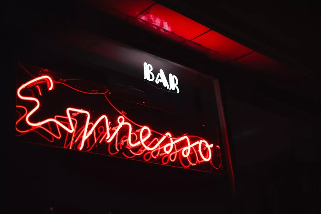 Ein rotes Neonschild mit der Aufschrift "Espresso" und ein weißes "BAR"-Schild darüber leuchten in der dunklen Umgebung und erinnern an das pulsierende Nachtleben Mallorcas.