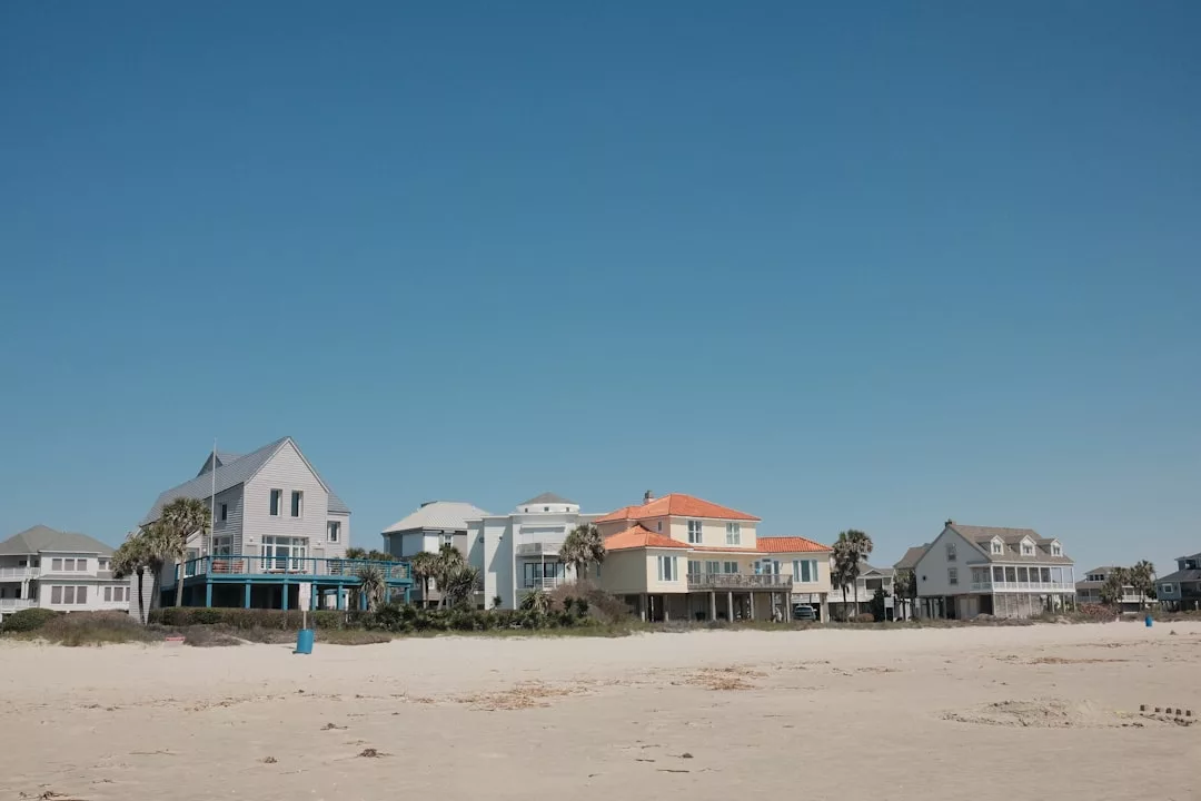 Reihen von Strandhäusern mit Palmen säumen die sandige Küste Mallorcas unter einem klaren blauen Himmel.