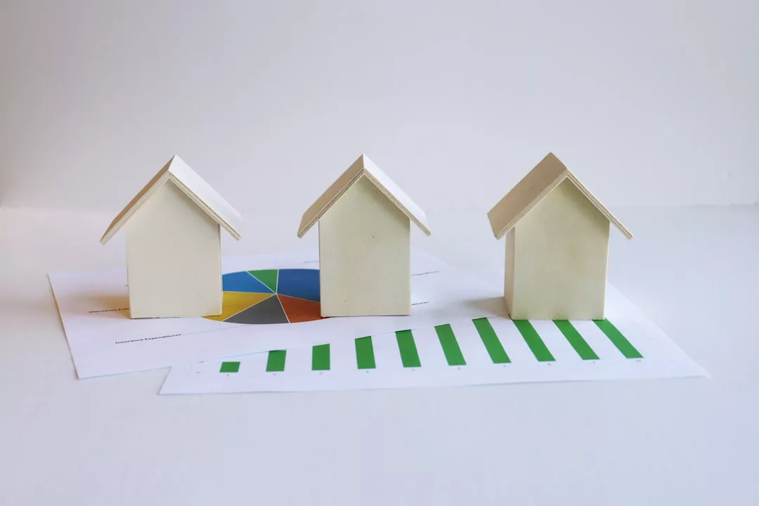Drei kleine Modellhäuser sind auf Torten- und Balkendiagrammen vor einem schlichten Hintergrund platziert und veranschaulichen die Immobilientrends auf Mallorca.
