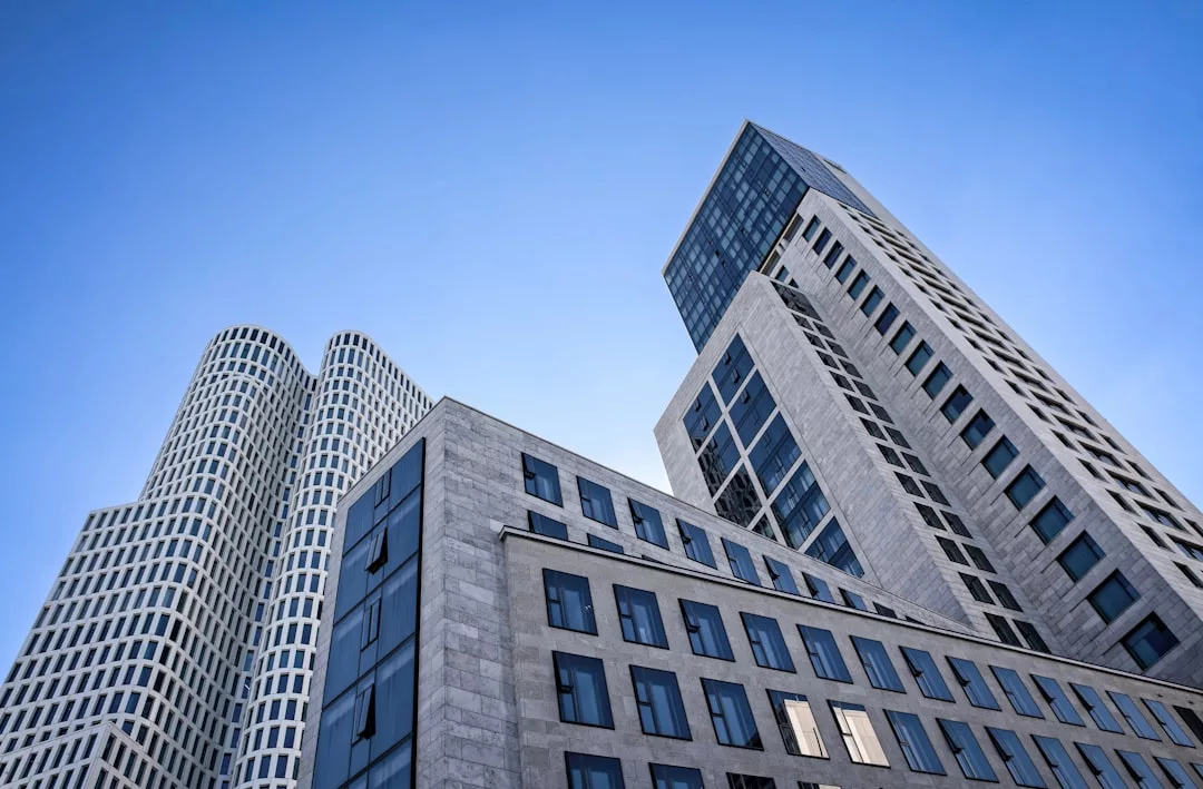 Moderne Hochhäuser mit Glas- und Steinfassaden ragen in die Höhe und erinnern an die moderne Skyline Mallorcas vor einem klaren blauen Himmel.