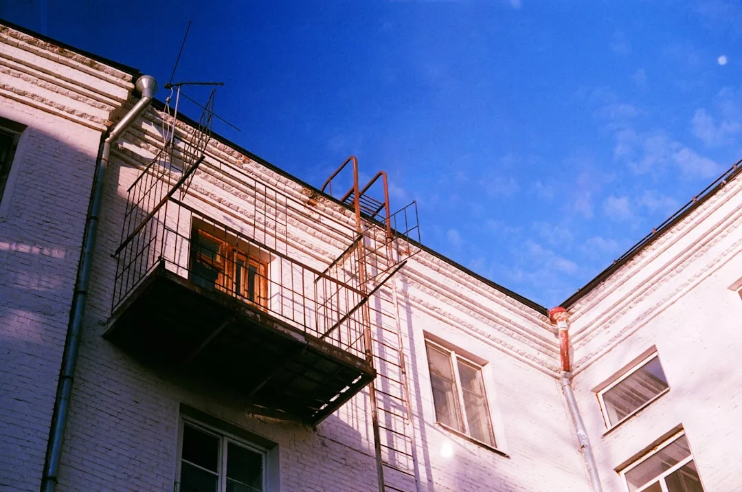 Ein Backsteingebäude mit einer metallenen Feuerleiter und einem Balkon vor dem klaren blauen Himmel Mallorcas.