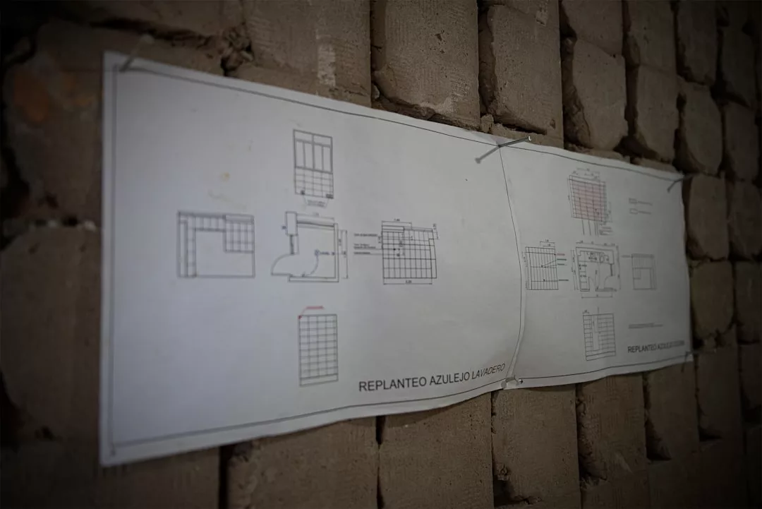 Zwei architektonische Entwürfe mit technischen Zeichnungen sind an eine rohe Ziegelwand auf Mallorca gepinnt. Die Pläne tragen den Titel "REPLANTEO AZULEJO LAVAZOSO".
