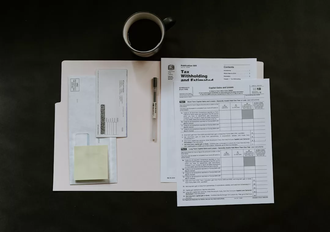 Ein Steuerformular, ein Stift, Umschläge, Haftnotizen und eine Tasse Kaffee stehen auf einer dunklen Fläche neben einem Aktenordner und erinnern an die Organisation von Papierkram für eine Reise nach Mallorca.