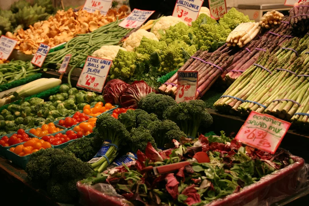 Ein Marktstand auf Mallorca bietet eine Vielzahl von frischem Gemüse an, darunter Brokkoli, Spargel, Rosenkohl, Tomaten, Grünzeug und Pilze - alle mit handgeschriebenen Preisschildern.
